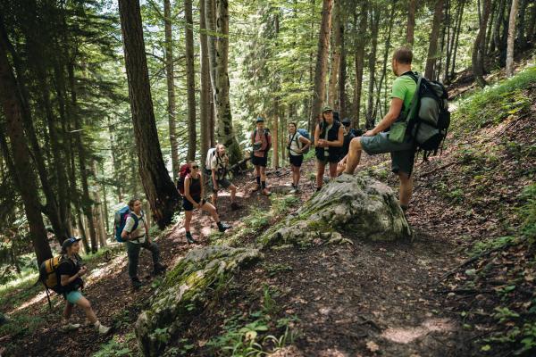 Eine Gruppe von Personen steht zusammen auf einem steilen Wanderweg im Wald