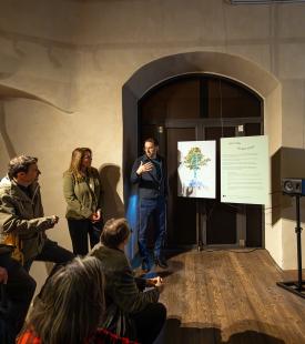 Vor einem großen Torbogen im inneren des Schloss Orth werden zwei Bilder der neuen Ausstellung präsentiert