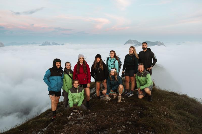 Gruppenfoto von 10 Personen auf einem Gipfel, dahinter der Morgennebel