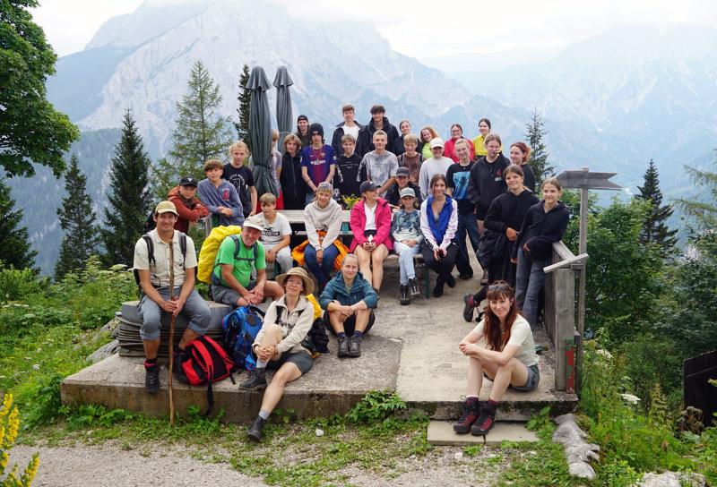 Eine Gruppe von Kindern sitzt zusammen vor einem Bergpanorama