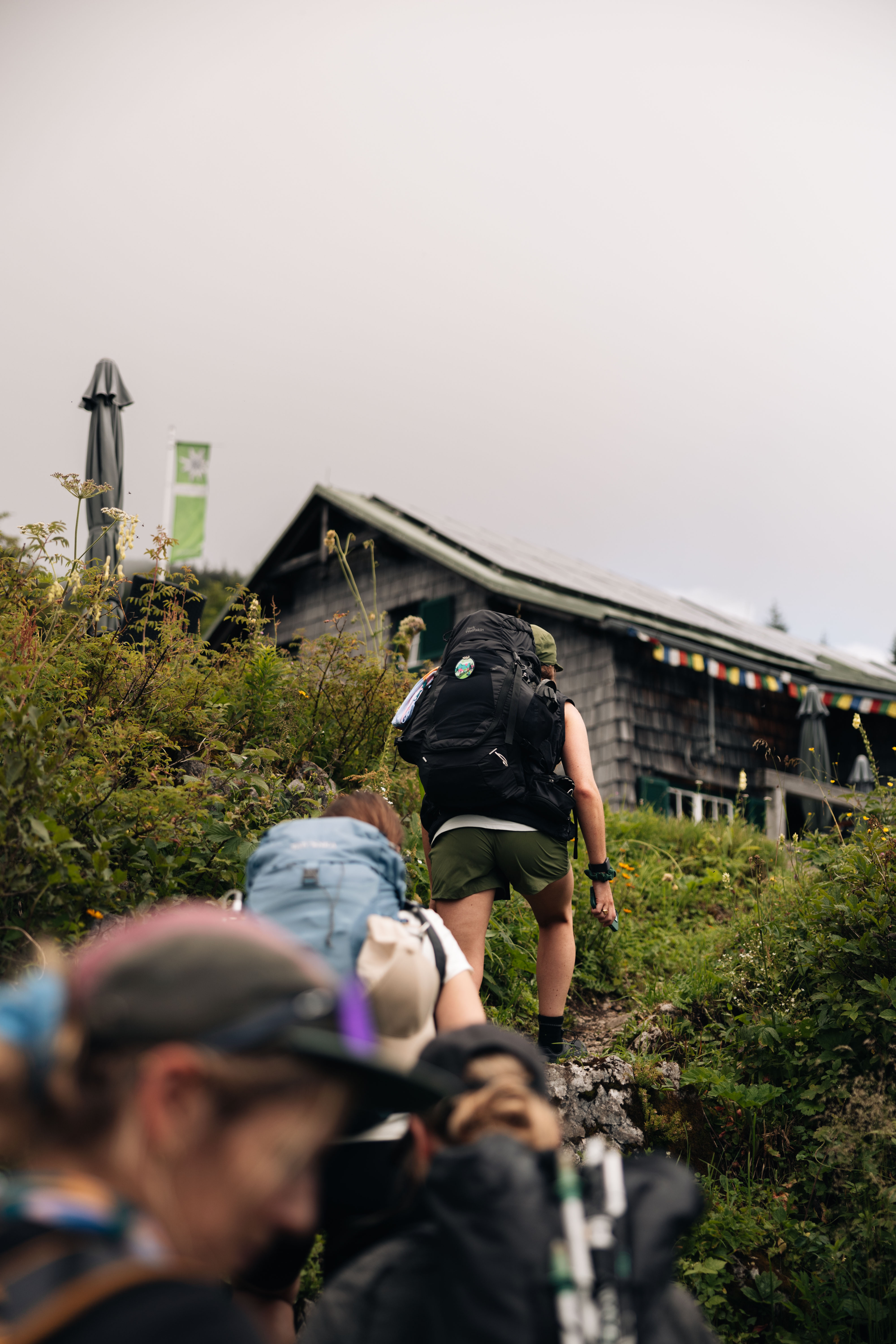 Eine Gruppe von Personen gehen einen Weg zu einer Hütte hinauf