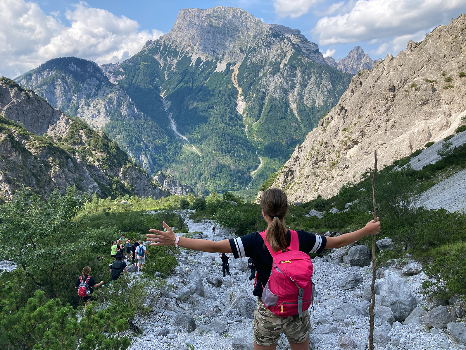 Ein Junge steht mit ausgebreiteten Armen oben auf einem Schuttflur, ein Berg ist im Hintergrund zu sehen